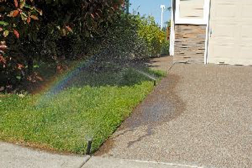 sprinkler heads overspraying a driveway
